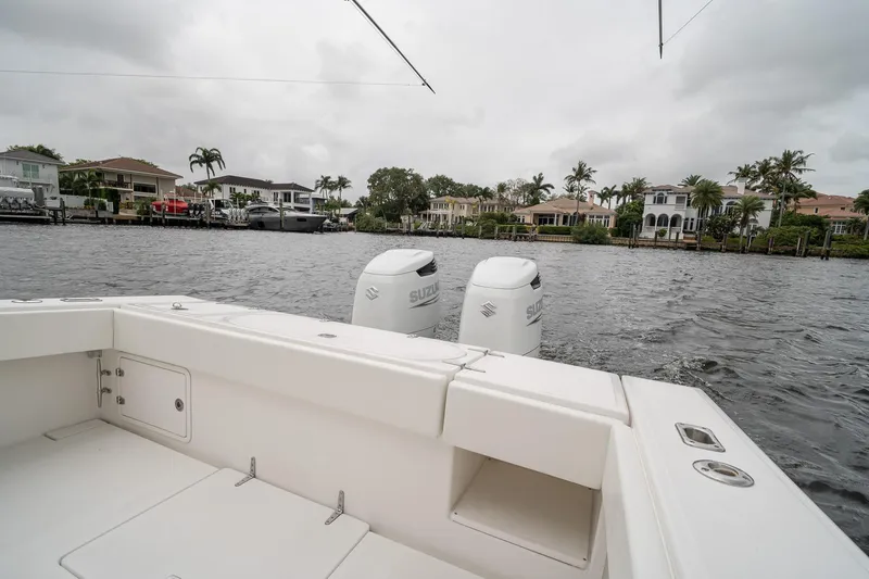 Slide: The Image of 2006 Venture Center Console boat with dual Suzuki engines on a waterfront. - 49