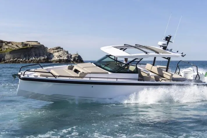 The Image of 2027 Axopar 37 Sun-Top cruising on ocean near rocky coastline. - 0