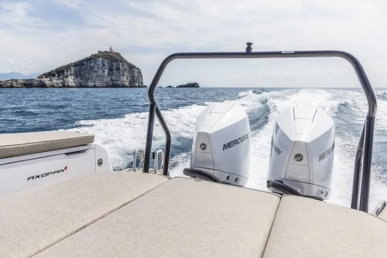 Slide: The Image of 2027 Axopar 37 Sun-Top boat cruising with twin Mercury engines, scenic ocean view. - 8