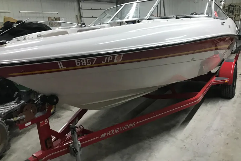 The Image of 2002 Four Winns 180 Horizon boat on red trailer in garage setting. - 1