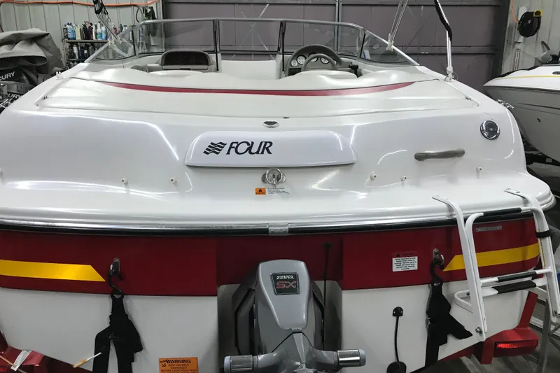 Slide: The Image of 2002 Four Winns 180 Horizon boat in a garage, featuring a white and red exterior. - 4