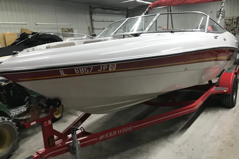 Slide: The Image of 2002 Four Winns 180 Horizon boat on a red trailer in a garage setting. - 5