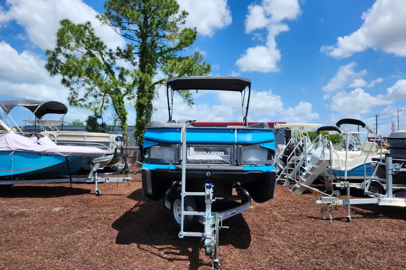 Slide: The Image of 2023 Sea-Doo Switch Cruise 21 pontoon boat on trailer under blue sky. - 2