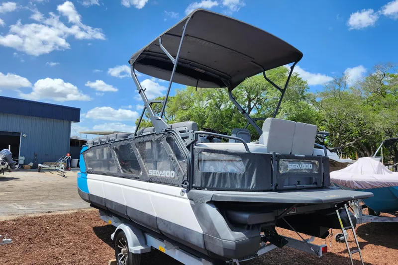 Slide: The Image of 2023 Sea-Doo Switch Cruise 21 pontoon boat with canopy, parked outdoors under blue sky. - 6