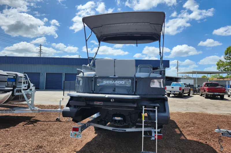 Slide: The Image of 2023 Sea-Doo Switch Cruise 21 pontoon boat with canopy, parked outdoors under blue sky. - 7