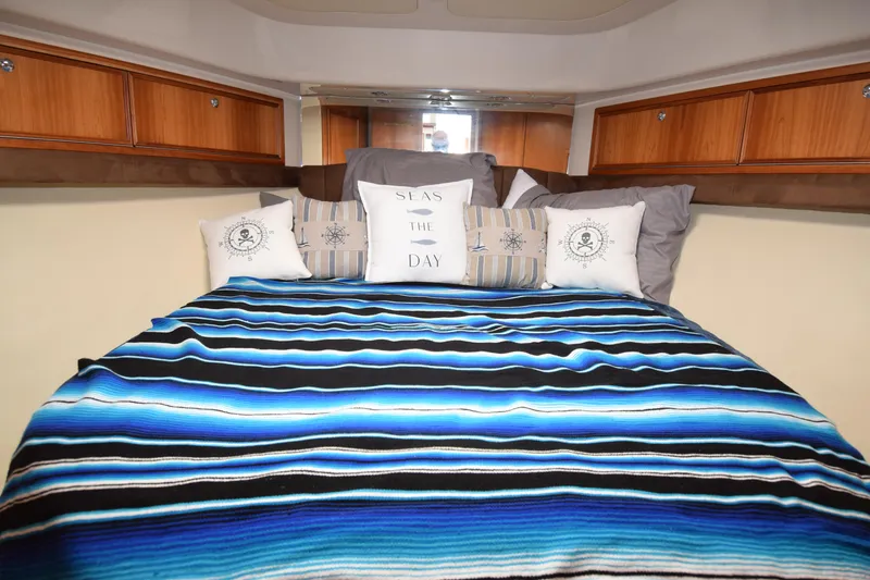 Slide: The Image of Cozy bedroom in 2005 Riviera 33 Open Flybridge with nautical-themed pillows and striped blanket. - 13