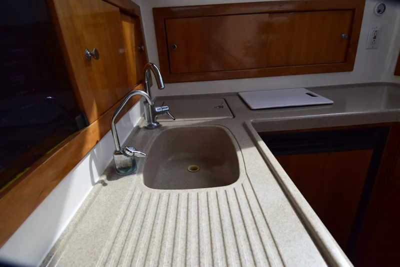 Slide: The Image of Kitchen sink area in 2005 Riviera 33 Open Flybridge yacht, featuring wooden cabinets. - 15