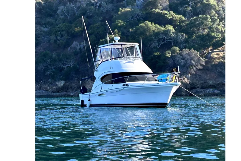Slide: The Image of 2005 Riviera 33 Open Flybridge yacht docked at marina under blue sky. - 2