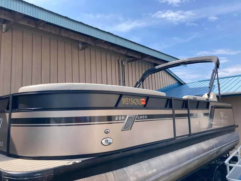 Slide: The Image of 2023 Viaggio Lago 22R pontoon boat parked by a building. - 2