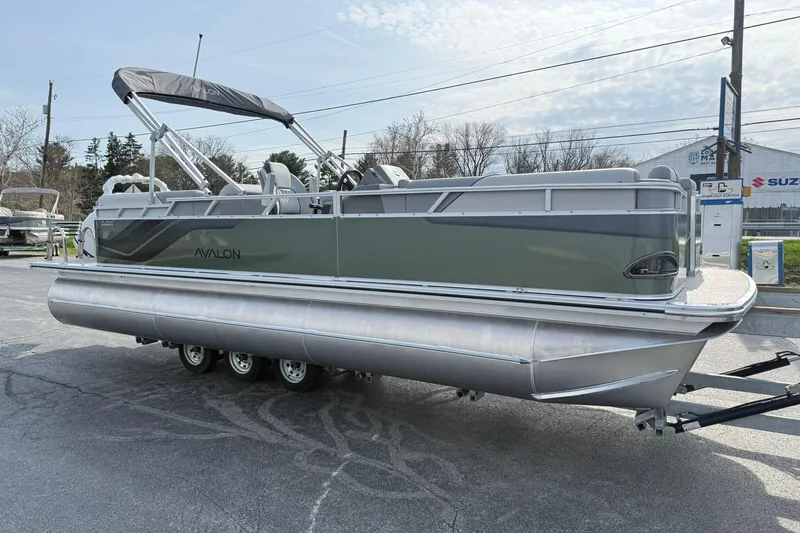 Slide: The Image of 2026 Avalon Venture Quad Lounge 23' pontoon boat on trailer, parked outdoors. - 6