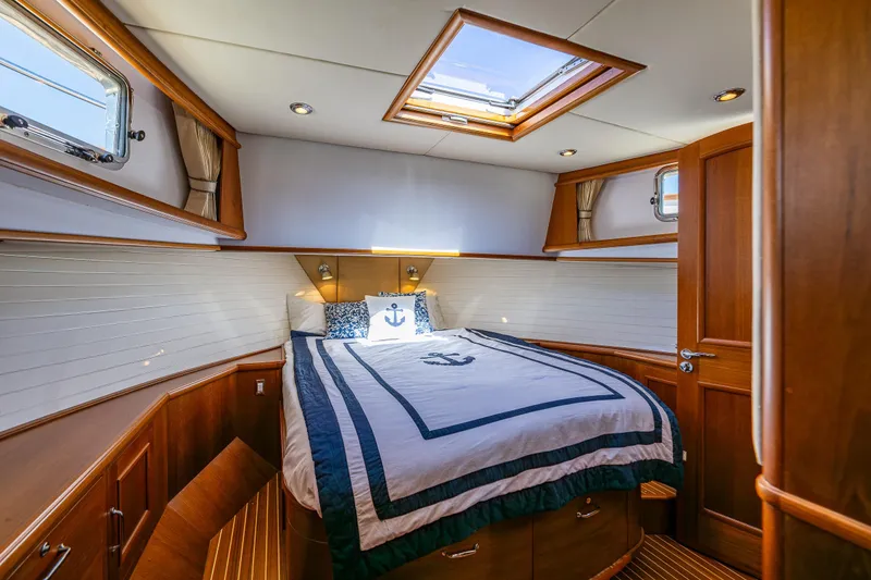 Slide: The Image of Luxurious 2006 Grand Banks 47 Europa yacht cabin with elegant wood finish and nautical bedding. - 12