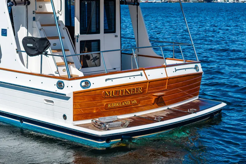 Slide: The Image of Grand Banks 47 Europa 2006 yacht on water, featuring wooden stern and "Mutineer" nameplate. - 9