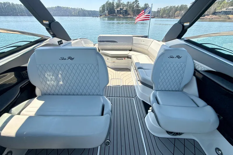 Slide: The Image of 2025 Sea Ray SLX 280 boat interior with luxurious seating and American flag on a serene lake. - 25