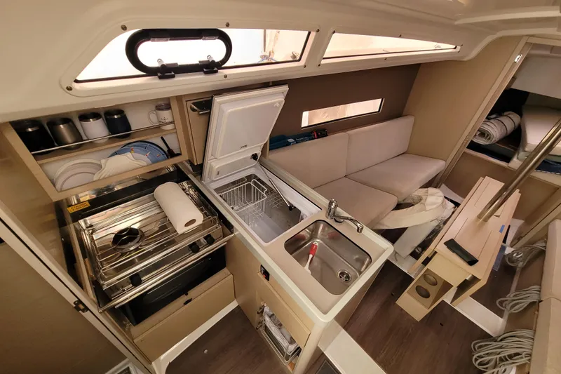 Slide: The Image of Interior of 2020 Beneteau Oceanis 30.1 yacht, featuring compact kitchen and seating area. - 26