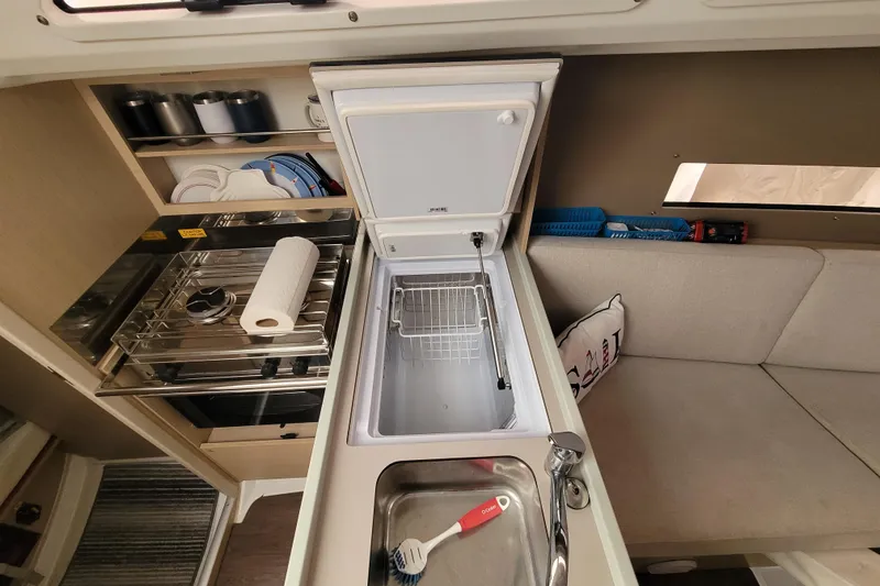 Slide: The Image of Interior of a 2020 Beneteau Oceanis 30.1 yacht kitchen with stove, fridge, and seating area. - 28