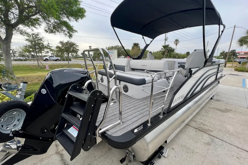 Slide: The Image of 2025 Harris Sunliner 230 pontoon boat with black canopy and gray seating. - 6