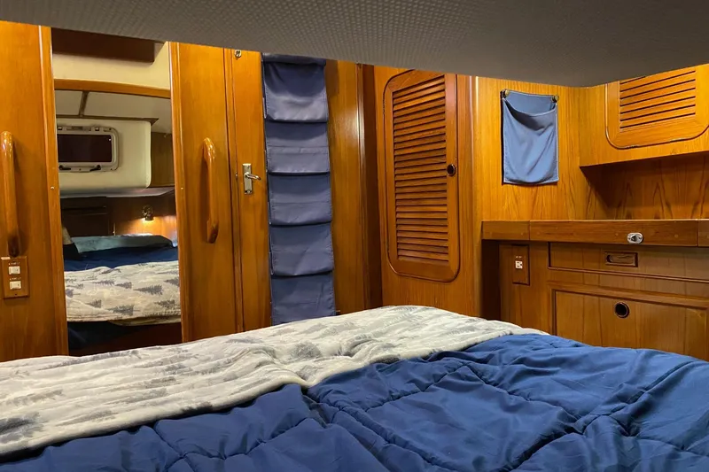 Slide: The Image of Cozy cabin bedroom in a 1988 Hylas 42 yacht with wooden interior and plush bedding. - 12