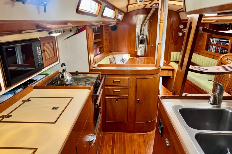 Slide: The Image of 1988 Hylas 42 sailboat cockpit with cushioned seating, docked on a serene green lake. - 2