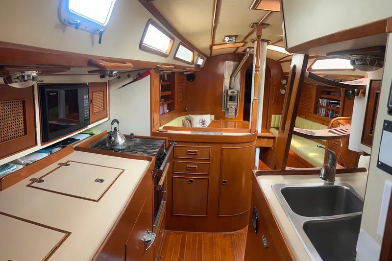 Slide: The Image of Interior of a 1988 Hylas 42 yacht featuring a wooden kitchen and cozy seating area. - 6