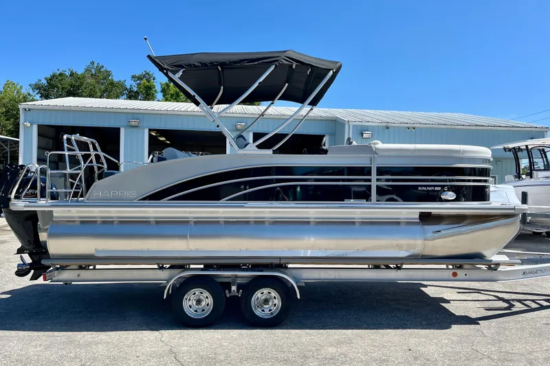 Slide: The Image of 2025 Harris Sunliner 210 pontoon boat on trailer outside warehouse. - 5