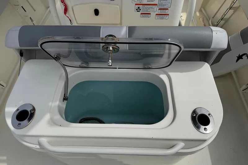 Slide: The Image of 2024 Mako 214 Center Console livewell with open lid and rod holders. - 16
