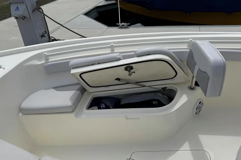 Slide: The Image of 2024 Mako 214 Center Console boat with open storage compartment and cushioned seating. - 25