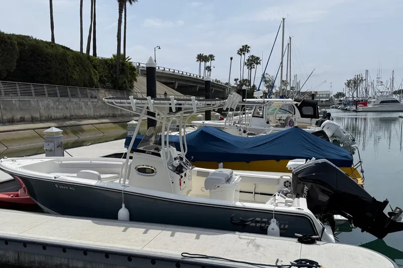 Slide: The Image of 2024 Mako 214 Center Console boat docked in a marina with palm trees. - 3