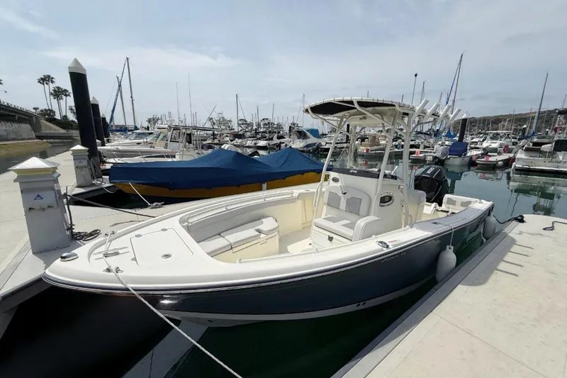 Slide: The Image of 2024 Mako 214 Center Console boat docked in a marina, surrounded by other vessels. - 4