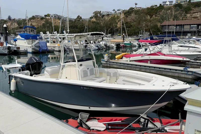 Slide: The Image of 2024 Mako 214 Center Console boat docked in a marina with other vessels. - 5