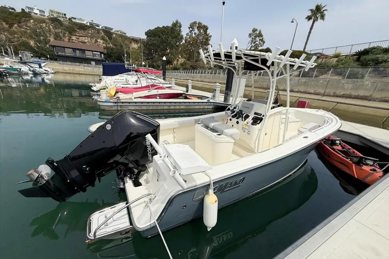 Slide: The Image of 2024 Mako 214 Center Console boat docked in a marina, featuring a powerful outboard motor. - 7