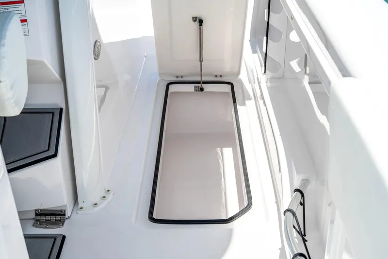 Slide: The Image of 2026 Twin Vee 340 GFX CC boat storage compartment, open hatch, white interior. - 6