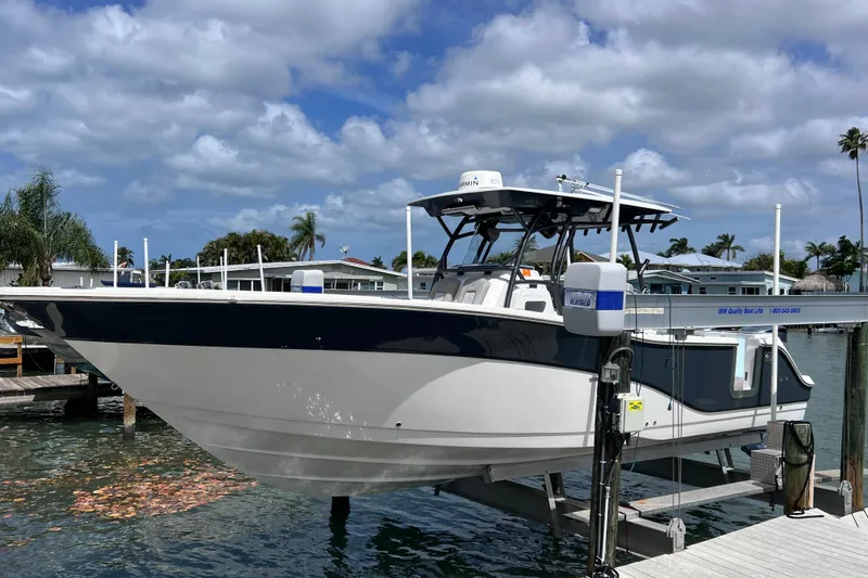 Slide: The Image of 2019 Sea Fox 328 Commander boat docked on a lift under a cloudy sky. - 10