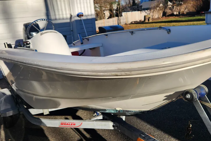 Slide: The Image of 2011 Boston Whaler 130 Super Sport boat on trailer, parked outdoors. - 3