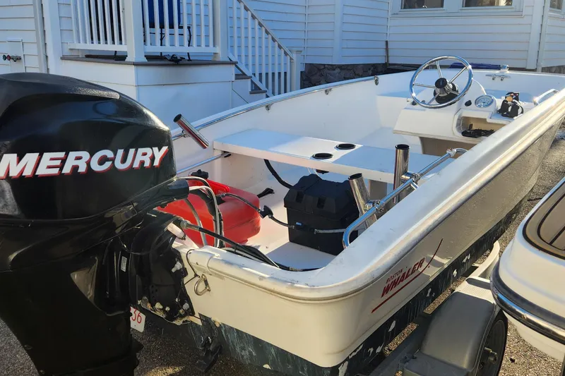 Slide: The Image of 2011 Boston Whaler 130 Super Sport boat with Mercury engine, parked near a house. - 6