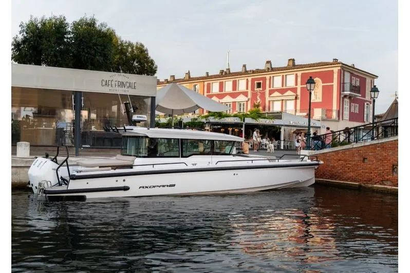 The Image of 2027 Axopar 37 XC Cross Cabin boat docked near a waterfront café. - 0