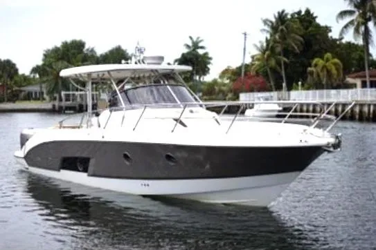 The Image of 2011 Sessa Marine Key Largo 36 yacht cruising on a calm waterway with lush greenery. - 1