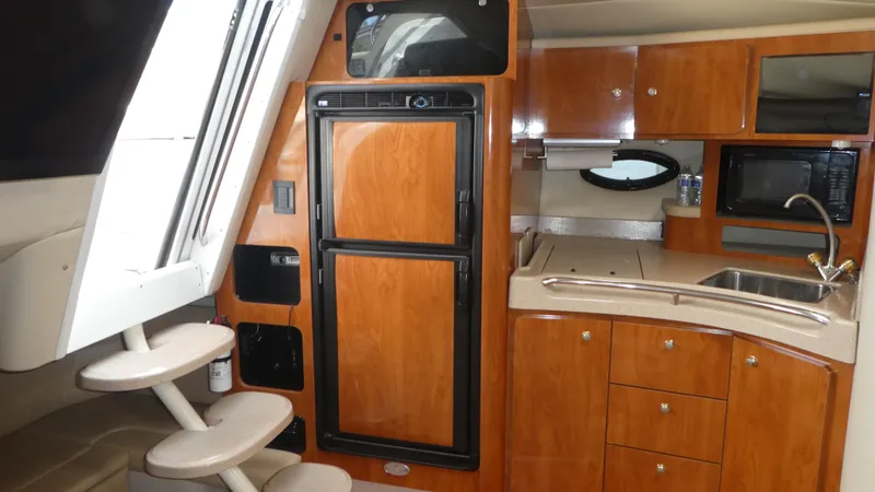 Slide: The Image of 2004 Larson 370 yacht interior with kitchenette, wooden cabinets, and stairs. - 20