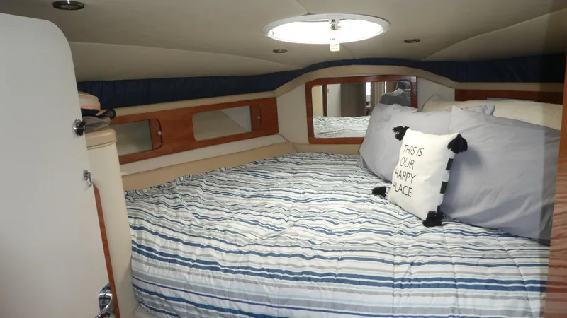 Slide: The Image of Cozy cabin interior of 2004 Larson 370 boat with striped bedding and decorative pillows. - 24