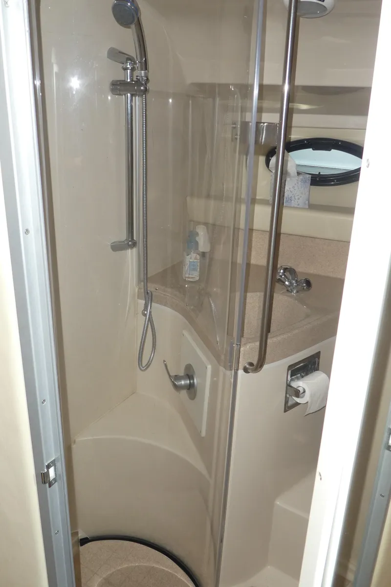 Slide: The Image of 2004 Larson 370 boat bathroom with shower, sink, and porthole window. - 26
