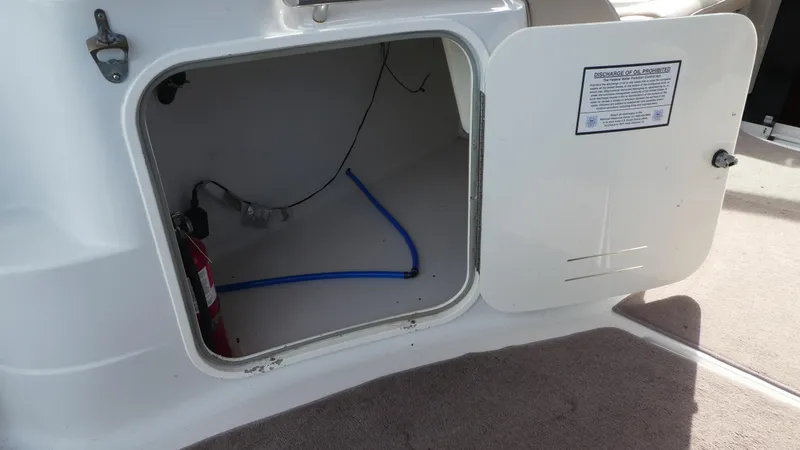 Slide: The Image of Open storage compartment on a 2004 Larson 370 boat, showing interior wiring and fire extinguisher. - 9