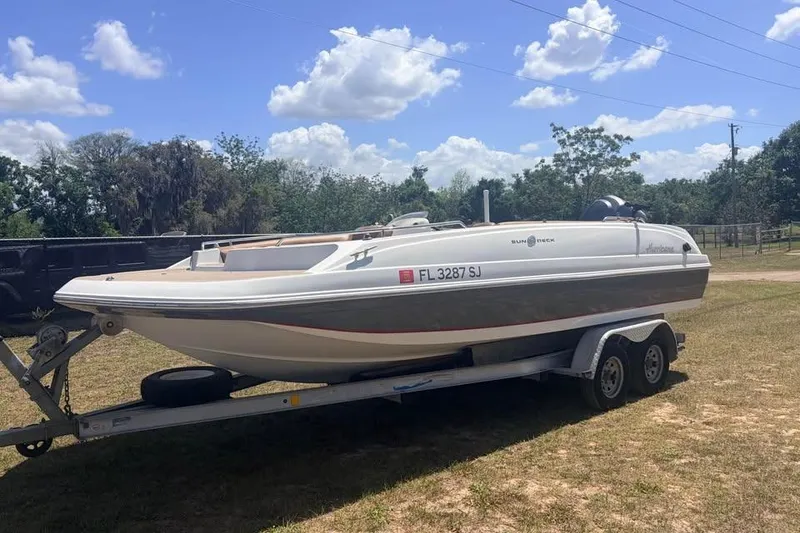 The Image of 2014 Hurricane SunDeck Sport 201 OB boat on trailer, parked outdoors under a blue sky. - 0