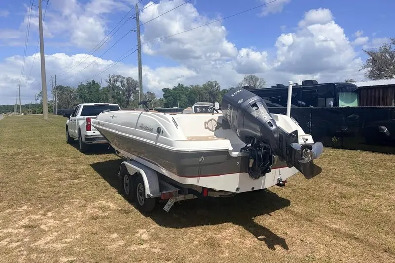 Slide: The Image of 2014 Hurricane SunDeck Sport 201 OB boat on trailer, parked outdoors under a cloudy sky. - 2