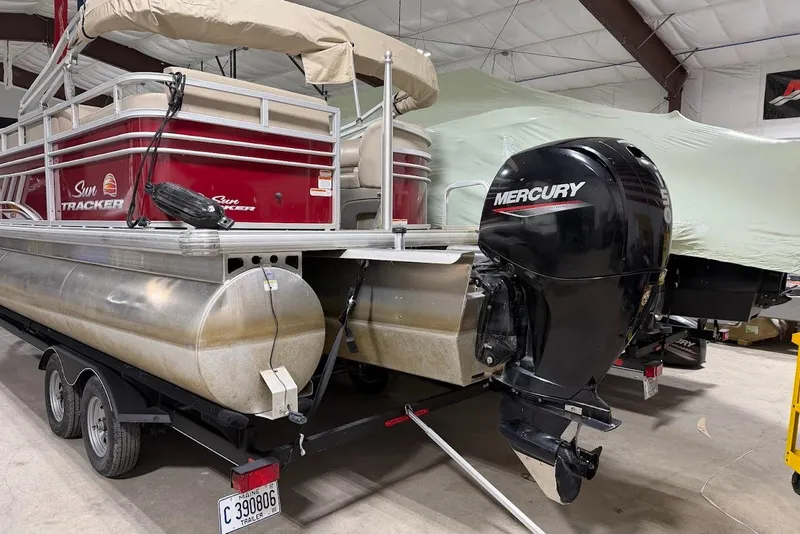 The Image of 2022 SUNTRACKER 22 DLX pontoon boat with Mercury outboard motor in a storage facility. - 1
