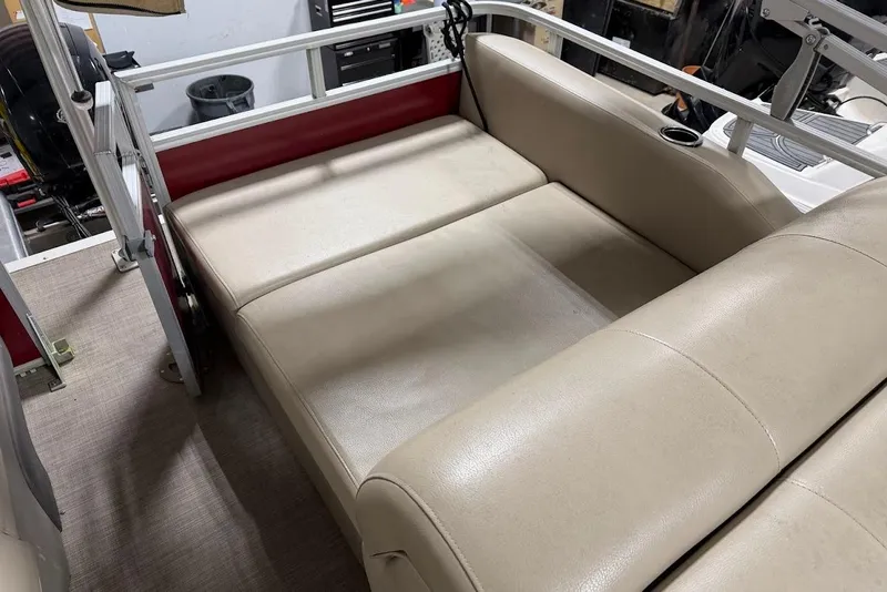 Slide: The Image of Beige seating area on 2022 SUNTRACKER 22 DLX boat, featuring cup holder and railing. - 11