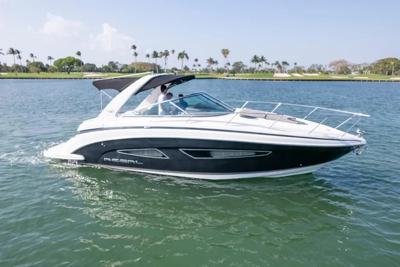 The Image of 2016 Regal 32 Express boat cruising on a sunny day, surrounded by calm waters and palm trees. - 0