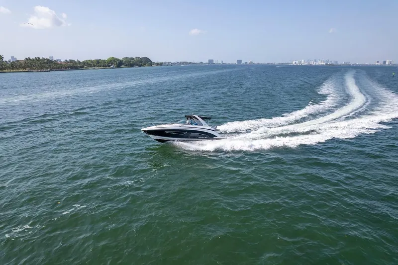 Slide: The Image of 2016 Regal 32 Express cruising on open water with city skyline in background. - 10