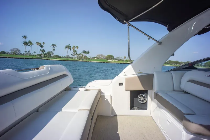 Slide: The Image of 2016 Regal 32 Express boat interior with luxurious seating, overlooking serene water and palm trees. - 16