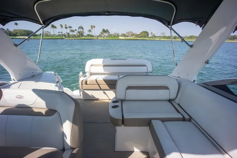 Slide: The Image of 2016 Regal 32 Express boat interior with seating, overlooking calm water and palm trees. - 18