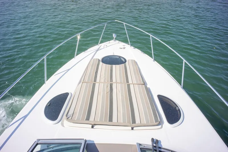 Slide: The Image of Bow view of 2016 Regal 32 Express yacht with striped sun pad on calm water. - 23