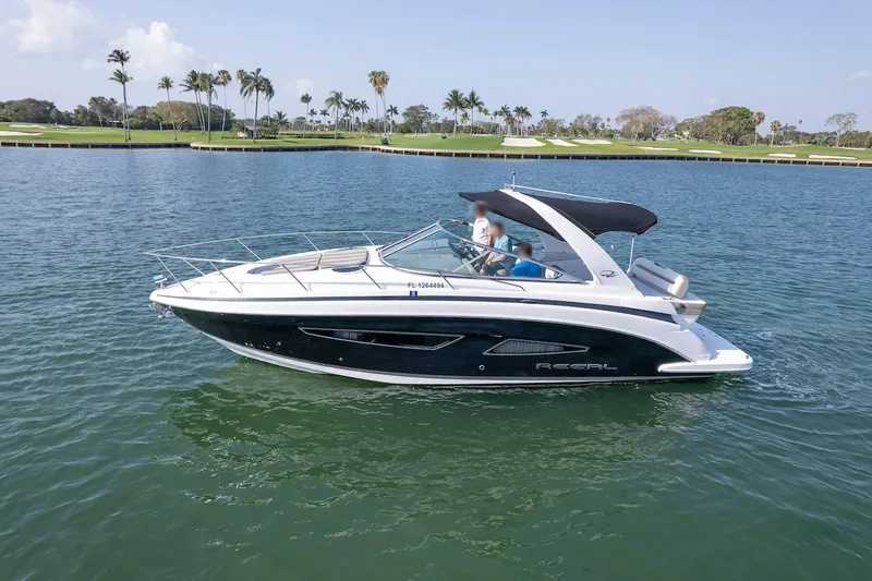 Slide: The Image of 2016 Regal 32 Express boat cruising on a calm lake with palm trees in the background. - 5